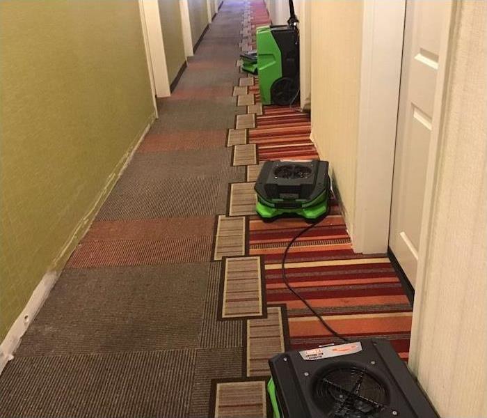 Hotel hallway with fans and dehumidifiers set on the floor