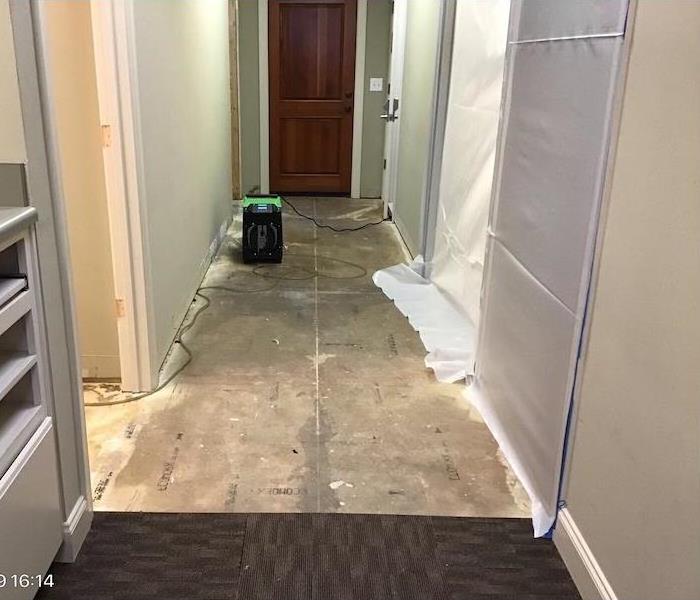 hallway with plastic barriers and removed carpet tiles