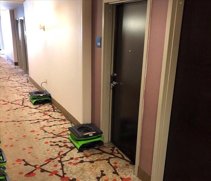 Carpeted hallway with SERVPRO drying equipment in front of doors